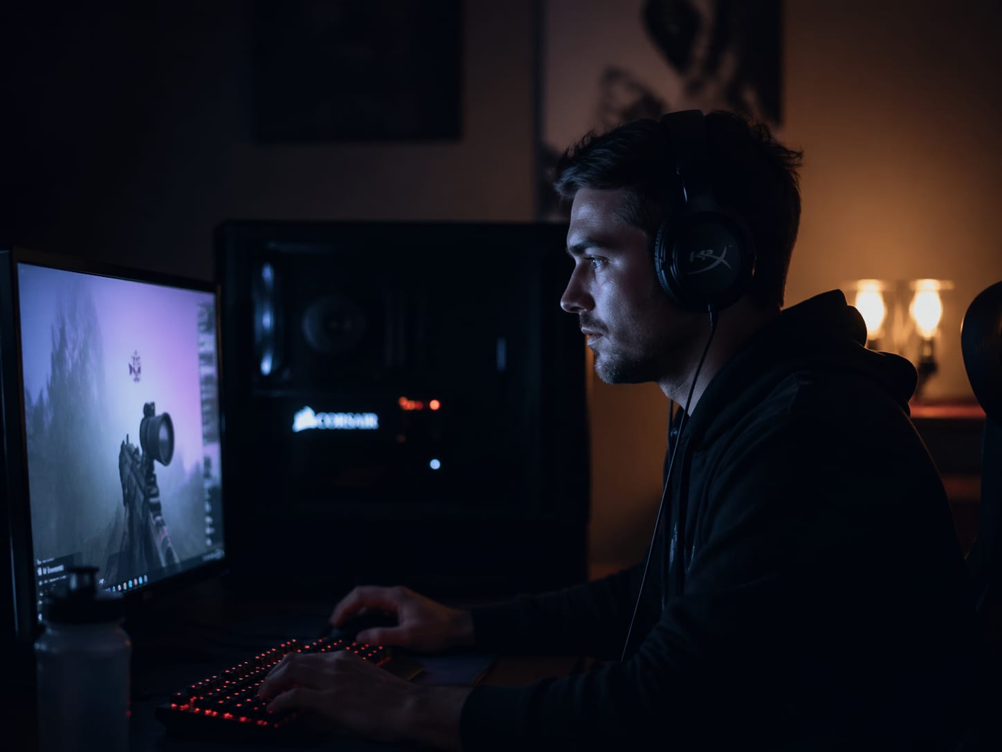 Jugador en una habitación tenue durante una sesión nocturna con auriculares y el resplandor ambiental de la pantalla