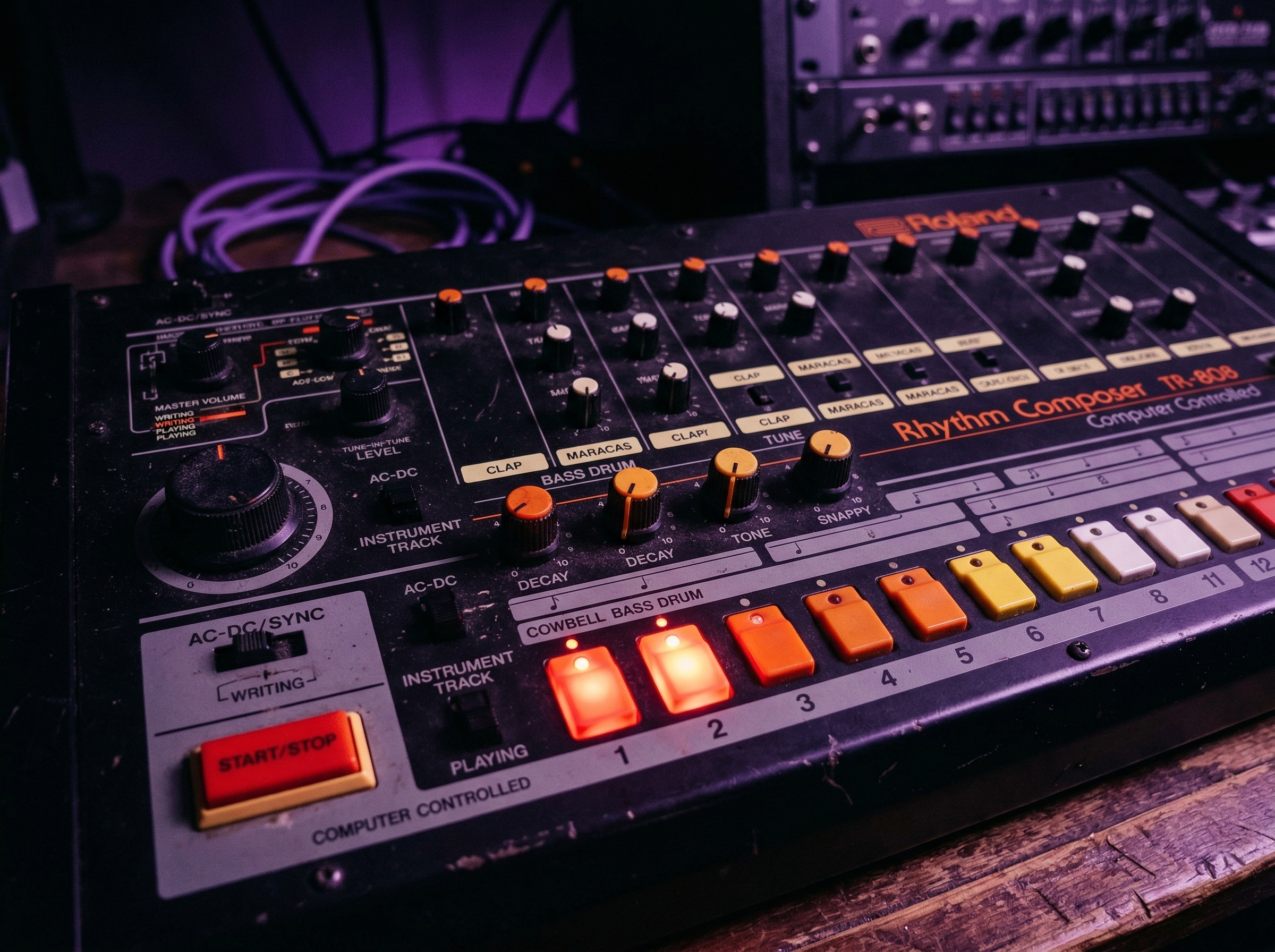 Close-up of TR-808 drum machine with glowing bass and cowbell pattern indicators